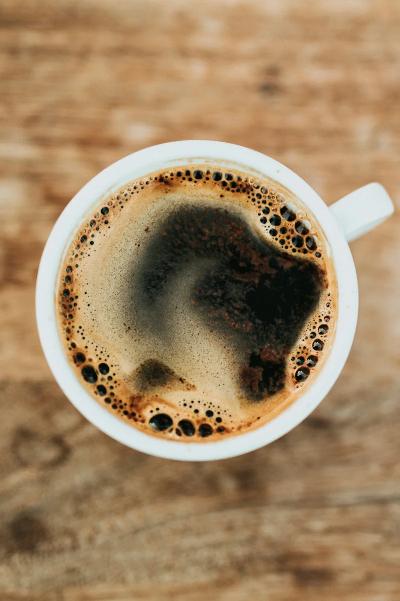 A cup of black coffee on a wooden table.